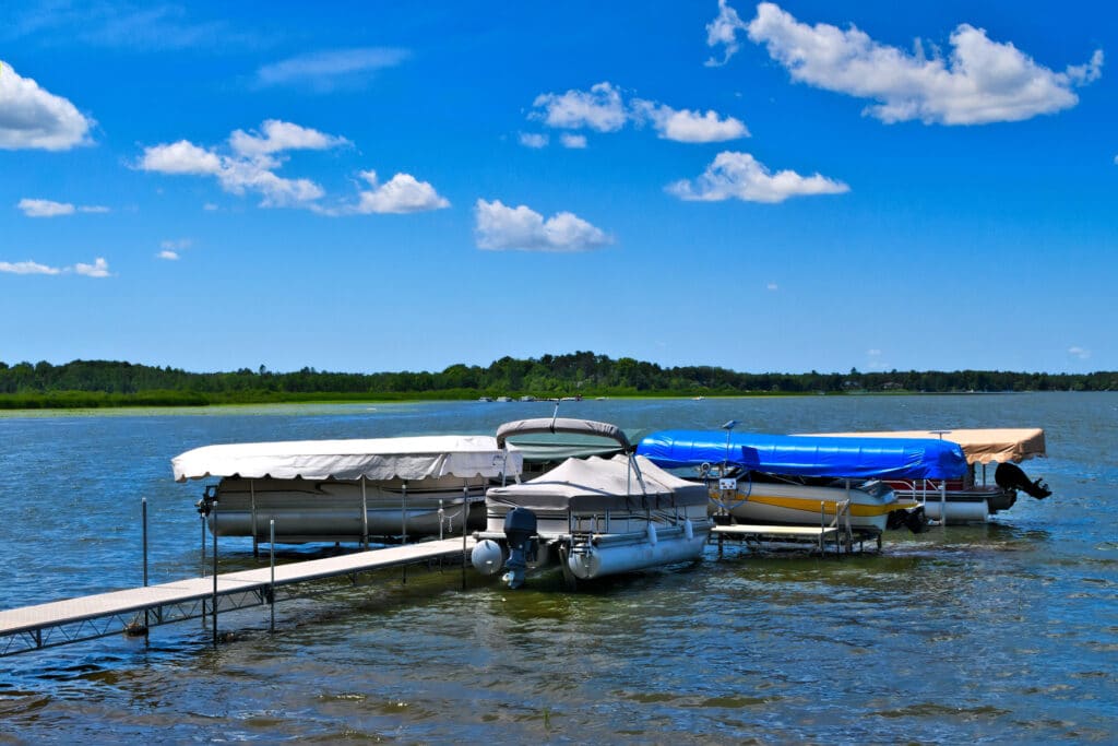 There are 4 boats in boat lifts with bost lift canopies on the water.